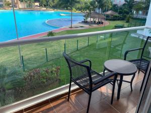坎昆Departamento 'Hozanek' en Dream Lagoons Cancun的一个带桌椅的阳台和一个游泳池