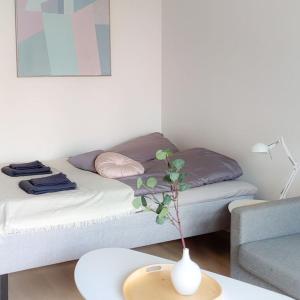 万塔New studio Pastel near Helsinki airport in Kivistö的一间设有床铺和一张桌子上的花瓶的房间