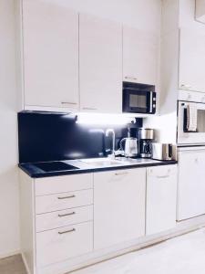 万塔New Studio Ruby near Helsinki Airport in Kivistö的厨房配有白色橱柜和黑色台面