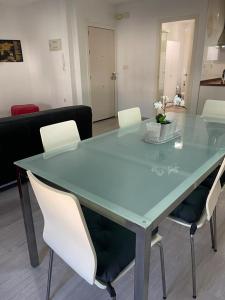 克雷维连特Lujoso y amplio apartamento en Crevillente的客房内的玻璃桌和白色椅子