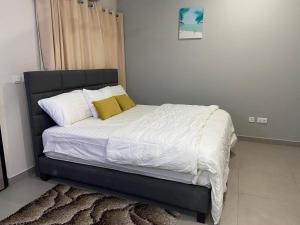 阿克拉Queens View Apartment的一间卧室配有带白色床单和黄色枕头的床。