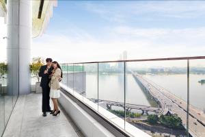 首尔Hotel Naru Seoul MGallery Ambassador的一对夫妇站在一座建筑物的顶端,望着水面