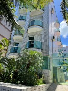 瓜鲁雅Apartamentos Primavera Guarujá的一座高大的建筑,前面有棕榈树