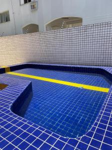 瓜鲁雅Apartamentos Primavera Guarujá的蓝色瓷砖和黄色条纹的游泳池