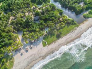 伯里塔卡Playa Bonita Hotel EcoCabañas Tayrona的享有树木和水面海滩的空中景致