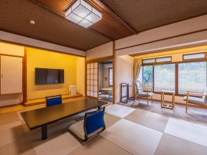 热海热海温泉山木日式旅馆的配有桌椅和电视的客房