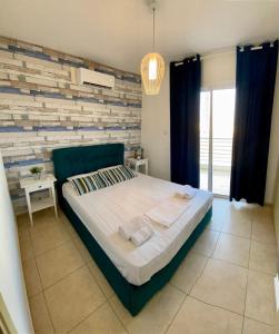 帕拉利米尼Mythical Sands Resort - Antonios的一间卧室设有一张床和砖墙
