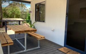 NicholsonLakes Bushland Caravan & Lifestyle Park的野餐桌和门廊上的长凳