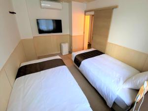 登别花钟亭花屋日式旅馆的一间卧室设有两张床,墙上配有电视。