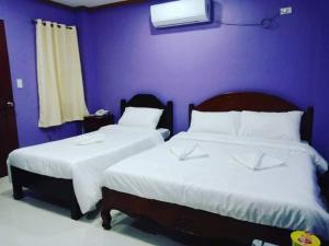 长滩岛OYO 926 Casa Venicia Caticlan的卧室设有两张床铺和紫色墙壁