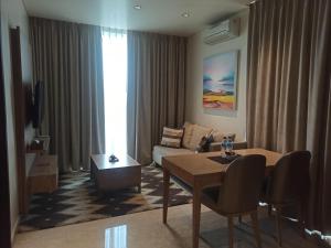 雅加达帕库布沃诺迪亚公寓式酒店的客厅配有桌子和沙发