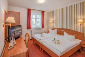 Usedom TownGasthaus Natzke的酒店客房设有一张大床和一台电视。