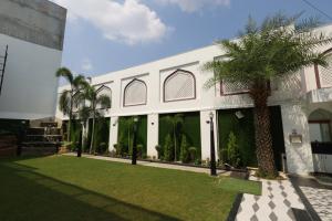 巴雷利Hotel Darbar-E-Khas A member of Crimson Hotels的一座白色的建筑,前面有棕榈树