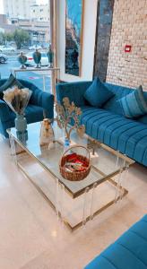 麦地那Taj Al Eiman Hotel的客厅配有蓝色的沙发和玻璃桌