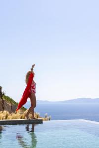 圣罗曼诺斯Kapsalos Villas的身穿红帽的女人站在游泳池旁边