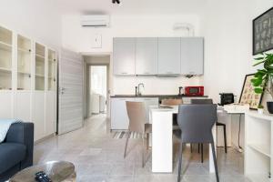 米兰La casa sull'albero City Life的厨房配有白色橱柜和桌椅