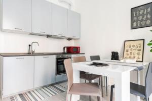 米兰La casa sull'albero City Life的厨房配有白色橱柜和白色的桌椅