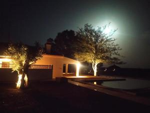 塞尔帕Quinta Marugo Retreats的一座房子在晚上点燃,前面有树木