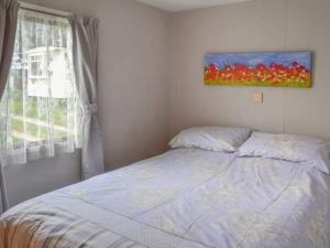 伯克顿Norfolk Poppy Caravan - Sleeps 4 - WiFi and Sky TV Included的卧室配有一张床,墙上挂有绘画作品