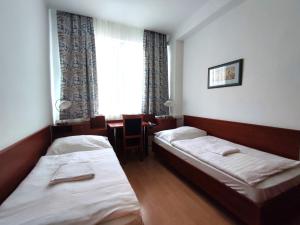 布拉迪斯拉发HOTEL JURKI Dom的客房设有两张床、一张桌子和一扇窗户。