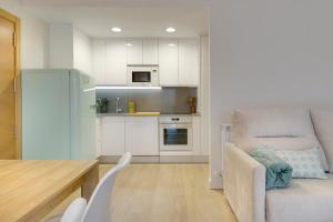 哈卡Apartamentos La muralla de Jaca的厨房配有白色橱柜、椅子和桌子