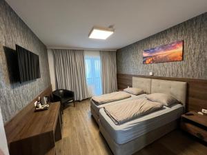 赫尔兴F Hotel的一间卧室配有一张床、一张书桌和一台电视