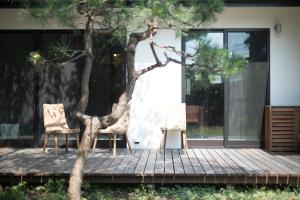 逗子市AMIGO HOUSE的木甲板上摆放着两把椅子和一棵树