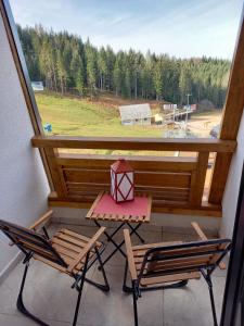 帕莱Apartman LeDa - Ski centar Ravna Planina Gornje Pale的阳台设有一张桌子和两把椅子,并设有一个窗户