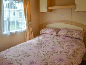 伯克顿Norfolk Lavender Caravan - Sleeps 4 - WiFi and Sky TV Included的一个小房间的一个床位,设有窗户