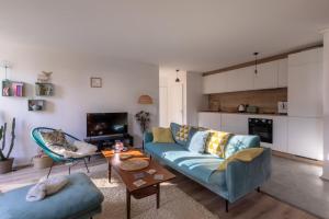 贝桑松Appartement très calme, terrasse & jardin en ville的客厅配有蓝色的沙发和桌子