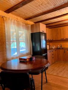 JieţCabană la poalele munților cu ciubăr的厨房配有木桌和黑冰箱。