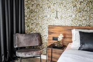 斯普利特Calma Luxury Rooms的一间卧室配有一张床、一把椅子和一面墙