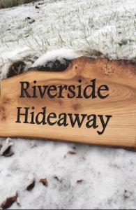 金克雷格Riverside Hideaway的雪上看河滨隐居之处的木标志