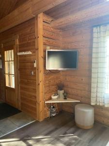 耶姆赛Latvahonka Cottage的一间带木墙、电视和凳子的房间
