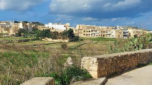 KerċemTrilogy, Ample Penthouse, Gozo的一座以石墙和建筑为背景的城市