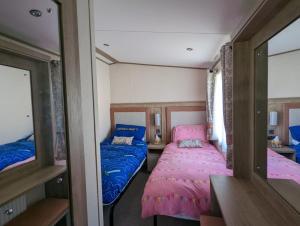 米尔福德昂西STUNNING LUXURY Caravan on edge of New Forest on SHOREFIELD Country Park ENTERTAINMENT AND LEISURE PASSES INCLUDED的小房间设有两张床和镜子