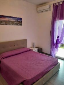 加比切马莱Residence Vigna del Mare的一间卧室配有一张带紫色床罩的床