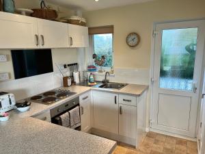 海景城2 Bedroom Bungalow SV58, Seaview, Isle of Wight Free Wi-Fi的厨房配有白色橱柜、水槽和窗户。