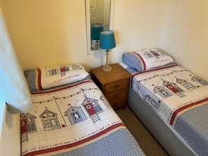 海景城2 Bedroom Bungalow SV58, Seaview, Isle of Wight Free Wi-Fi的带镜子的客房内的两张单人床