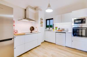 法鲁À dos Reis的厨房配有白色橱柜和硬木地板。