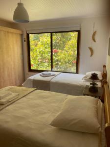 维库尼亚Casa Amatista Travels的带大窗户的客房内的两张床