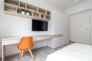 布加勒斯特Modern Apartment in the Heart of Bucharest的一间卧室配有书桌、电视和椅子