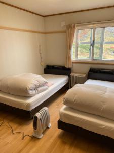 立山町Tengudaira Mountain Lodge的一间卧室配有两张床和风扇