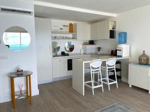 波拉波拉Studio Deluxe的厨房配有白色橱柜、桌子和凳子