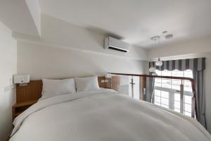 安平区安平肯辛顿旅店的卧室设有一张白色大床和一扇窗户。