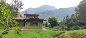 巴尼奥斯"Casa Verde" en Baños de Agua Santa con vista al volcán Tungurahua的一座小绿色房子,后面是群山