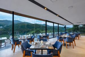 SoreangForest Hills Hotel的餐厅配有桌椅,位于山脉的背景中。