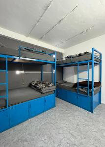 马拉里Young Monk Hostel & Cafe Old Manali的客房设有三张双层床和蓝色橱柜。