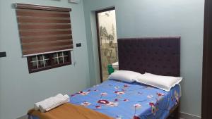 蓬蒂切里Tru Comfort的一间卧室配有一张带蓝色棉被的床和窗户。