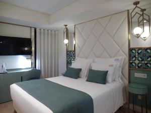里斯本New Style Lisbon Hotel的卧室配有一张白色大床和电视。